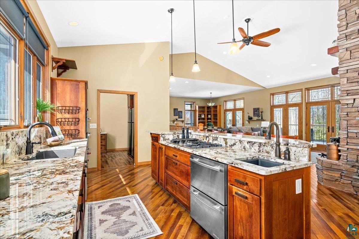 92598 Spells Road Sturgeon Lake, MN 55783 - Photo 59 of 60 Kitchen with light stone countertops, open floor plan, wood finish cabinets, a center island with sink, and lofted ceiling