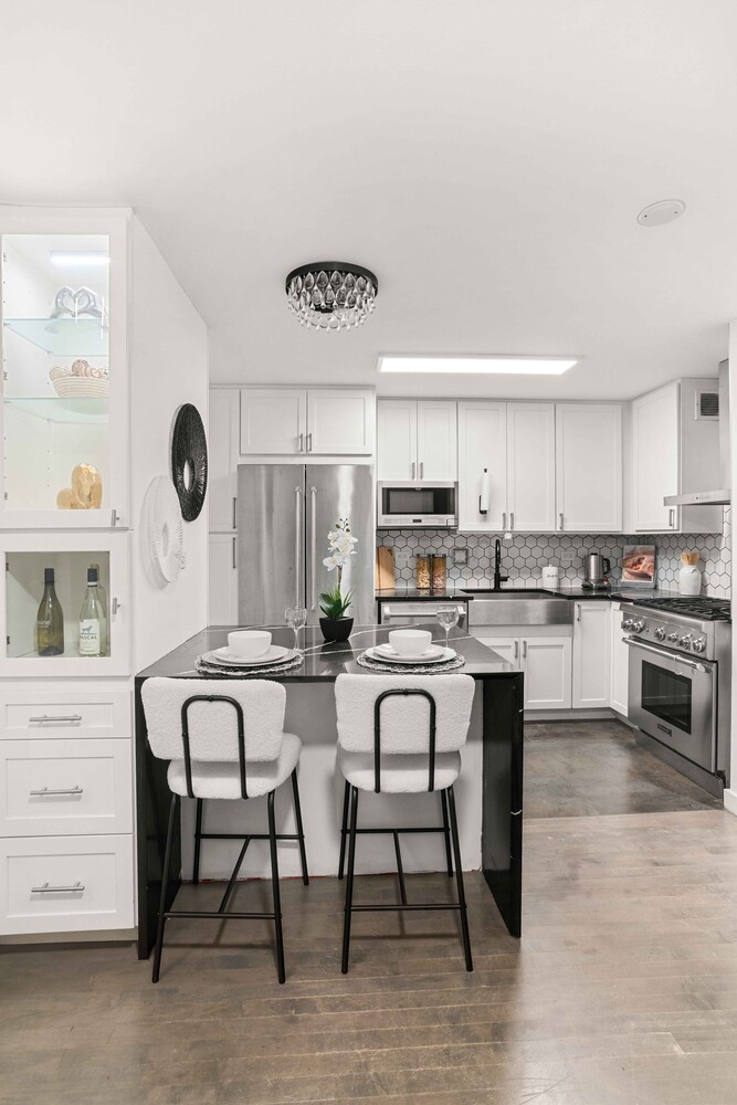 225 East 86th Street, Unit 204 Manhattan, NY 10028 - Photo 7 of 17 a kitchen with stainless steel appliances a table chairs microwave and cabinets