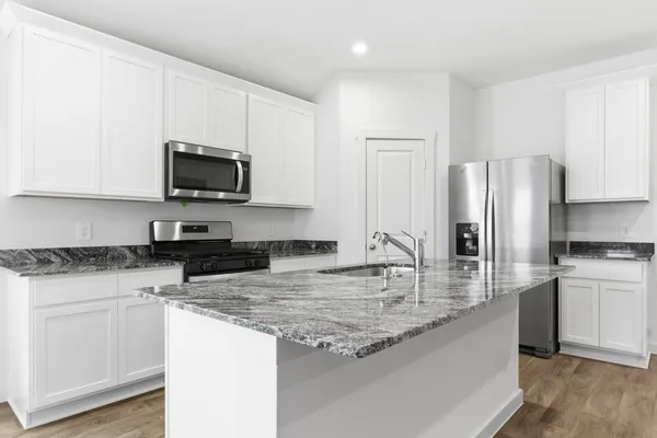 a kitchen with granite countertop a sink stove and refrigerator