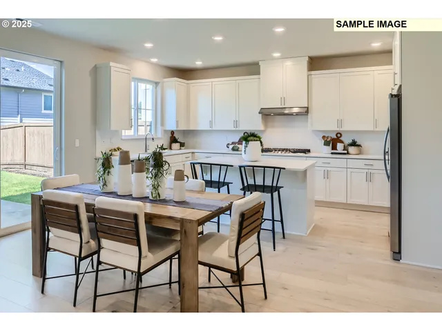 a kitchen with stainless steel appliances kitchen island granite countertop a dining table chairs sink and cabinets