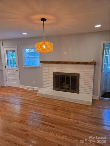 a view of a hallway with wooden floor and a bathroom