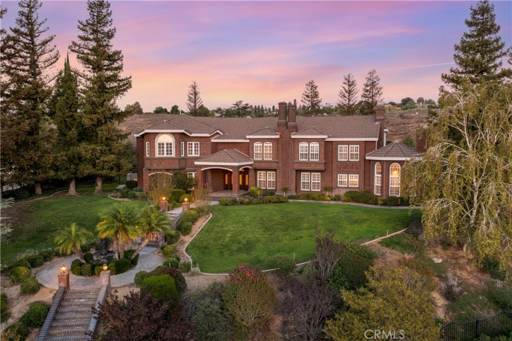 a view of a big house with a big yard and large trees