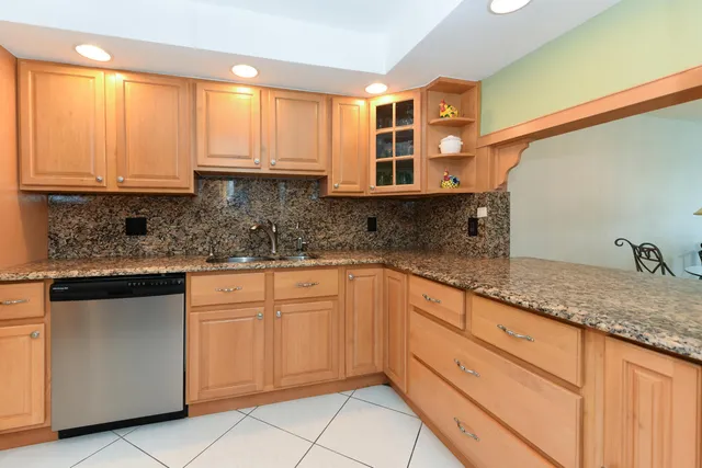 a kitchen with granite countertop white cabinets sink and window