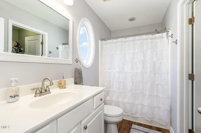 a bathroom with a sink toilet a mirror and shower curtain