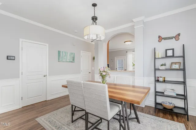 a dining room with wooden floor a chandelier a wooden table and chairs