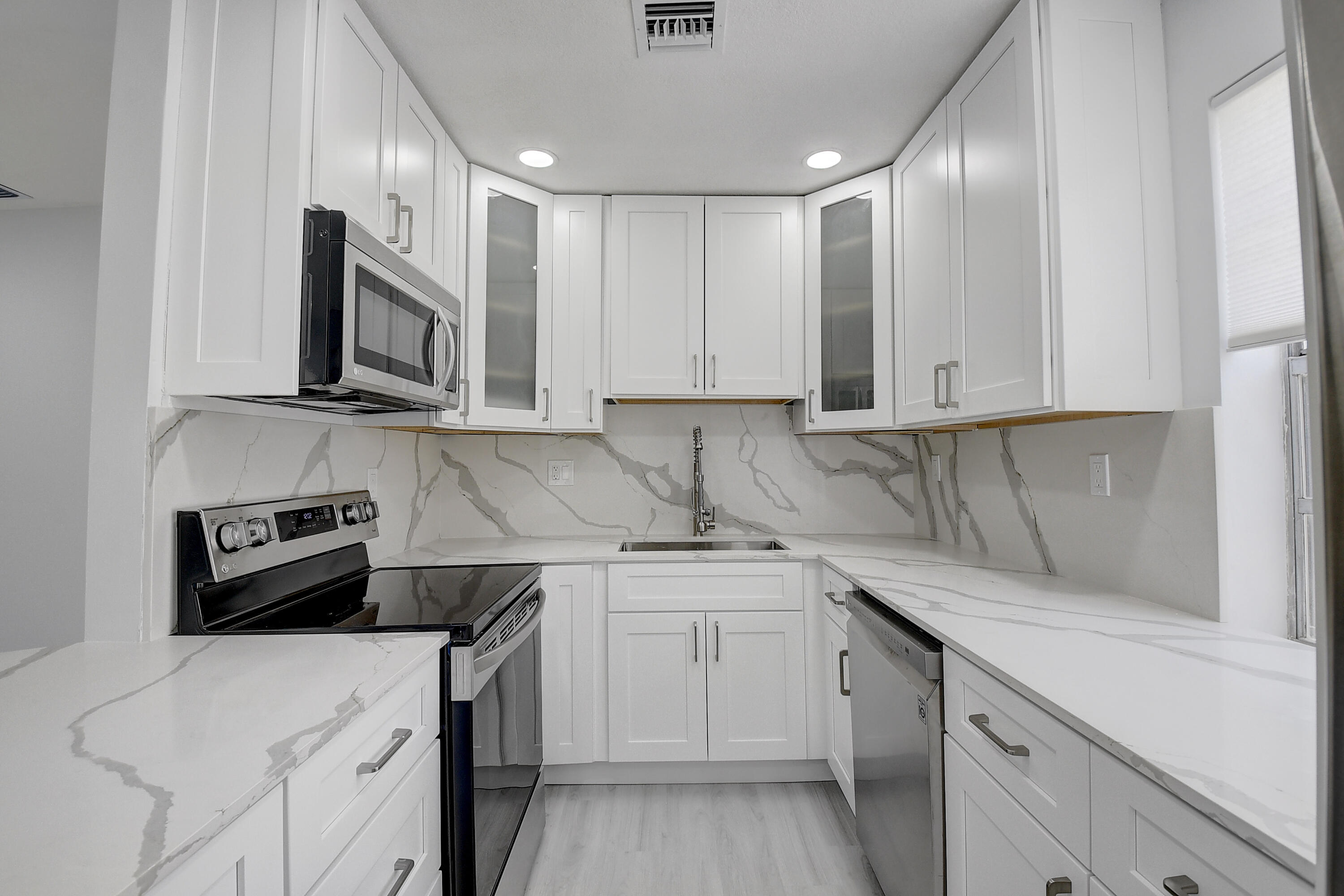 318 Monaco Boulevard, Unit G Delray Beach, FL 33446 - Photo 18 of 31 a kitchen with stainless steel appliances granite countertop a sink stove and microwave