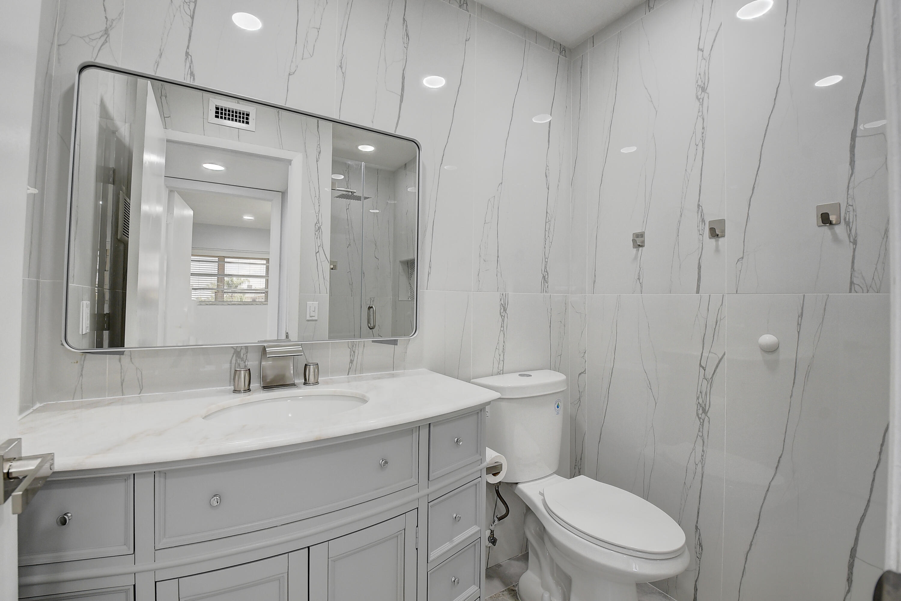 318 Monaco Boulevard, Unit G Delray Beach, FL 33446 - Photo 25 of 31 a bathroom with a sink a toilet a mirror and shower