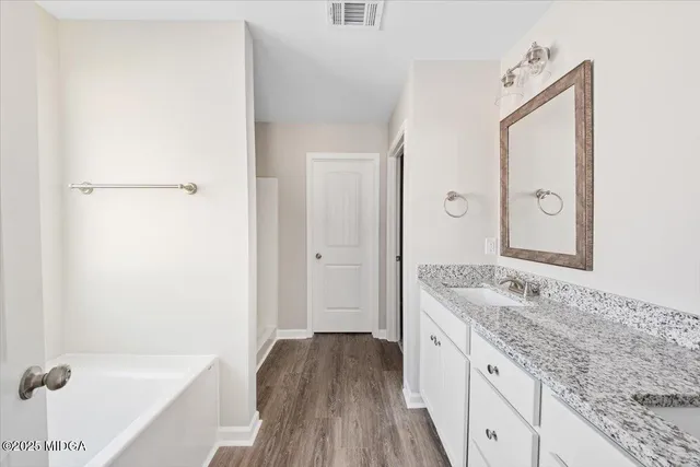 a spacious bathroom with a granite countertop sink and a mirror