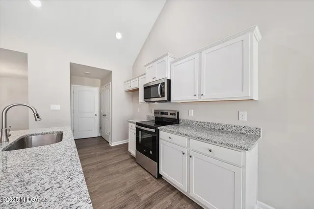 a kitchen with granite countertop white cabinets and stainless steel appliances