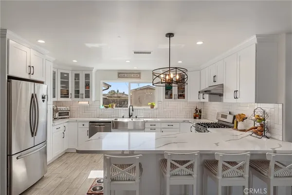 a kitchen with stainless steel appliances granite countertop a sink a stove a refrigerator and island with wooden floor