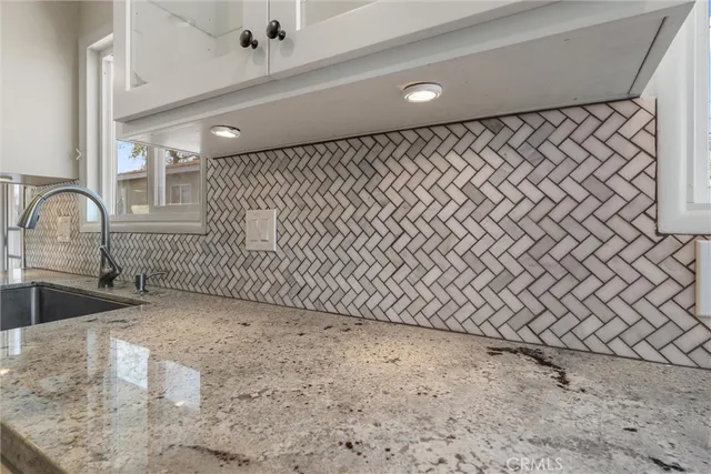 a kitchen with white cabinets and sink