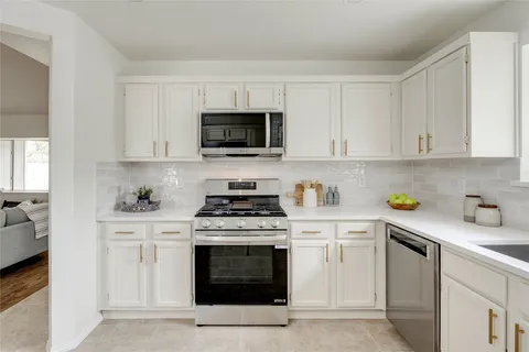 a kitchen with stainless steel appliances granite countertop grey cabinets a stove a sink and dishwasher