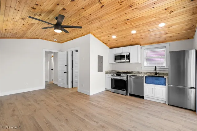 a kitchen with stainless steel appliances granite countertop a refrigerator a stove and a wooden floor