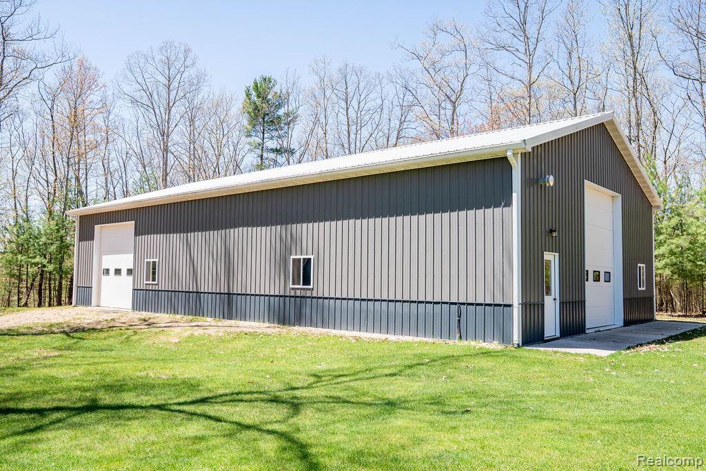 101 Highview Road Traverse City, MI 49696 - Photo 17 of 88 View of home's exterior featuring an outbuilding, a detached garage, a yard, and a metal roof