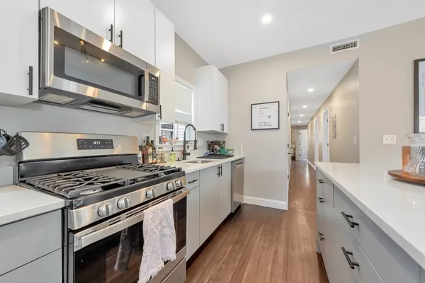 a kitchen with stainless steel appliances granite countertop a stove a sink and a microwave