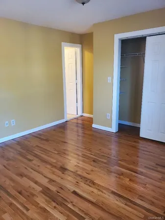 a view of an empty room with wooden floor and closet