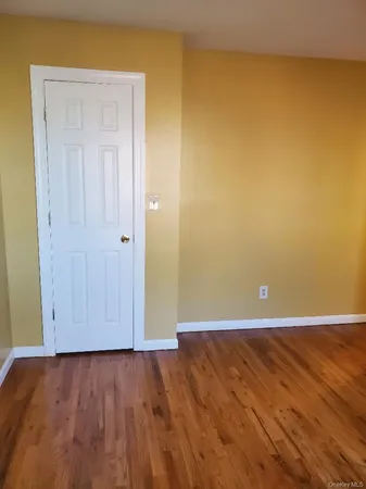 an empty room with wooden floor and closet area