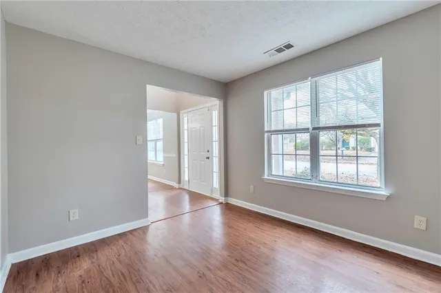 an empty room with wooden floor and windows