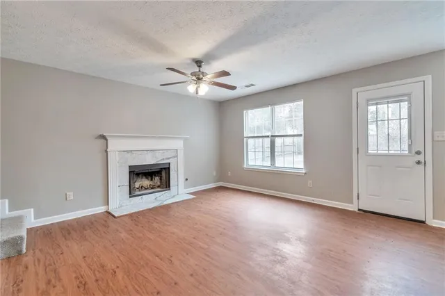 an empty room with windows fireplace and a wooden floor