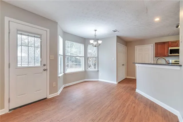 a view of an empty room with window and wooden floor