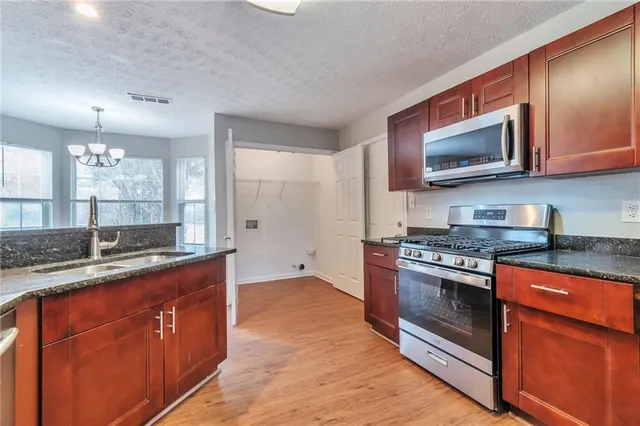 a kitchen with stainless steel appliances granite countertop a stove a sink and a microwave