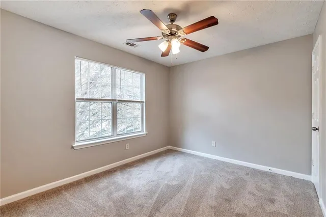 an empty room with windows and ceiling fan