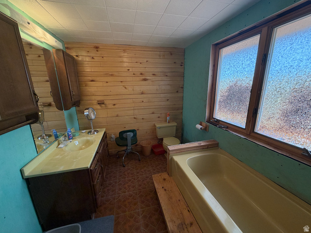 358 South Sky Drive Torrey, UT 84775 - Photo 32 of 82 Bathroom featuring a single vanity with an integrated sink, wood-finish cabinetry, shiplap accent wall, tiled flooring, and a bath/shower combination