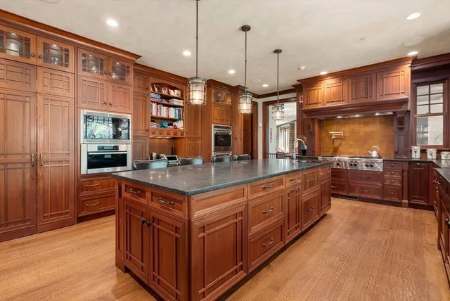 a large kitchen with stainless steel appliances granite countertop a stove a sink and a wooden floors