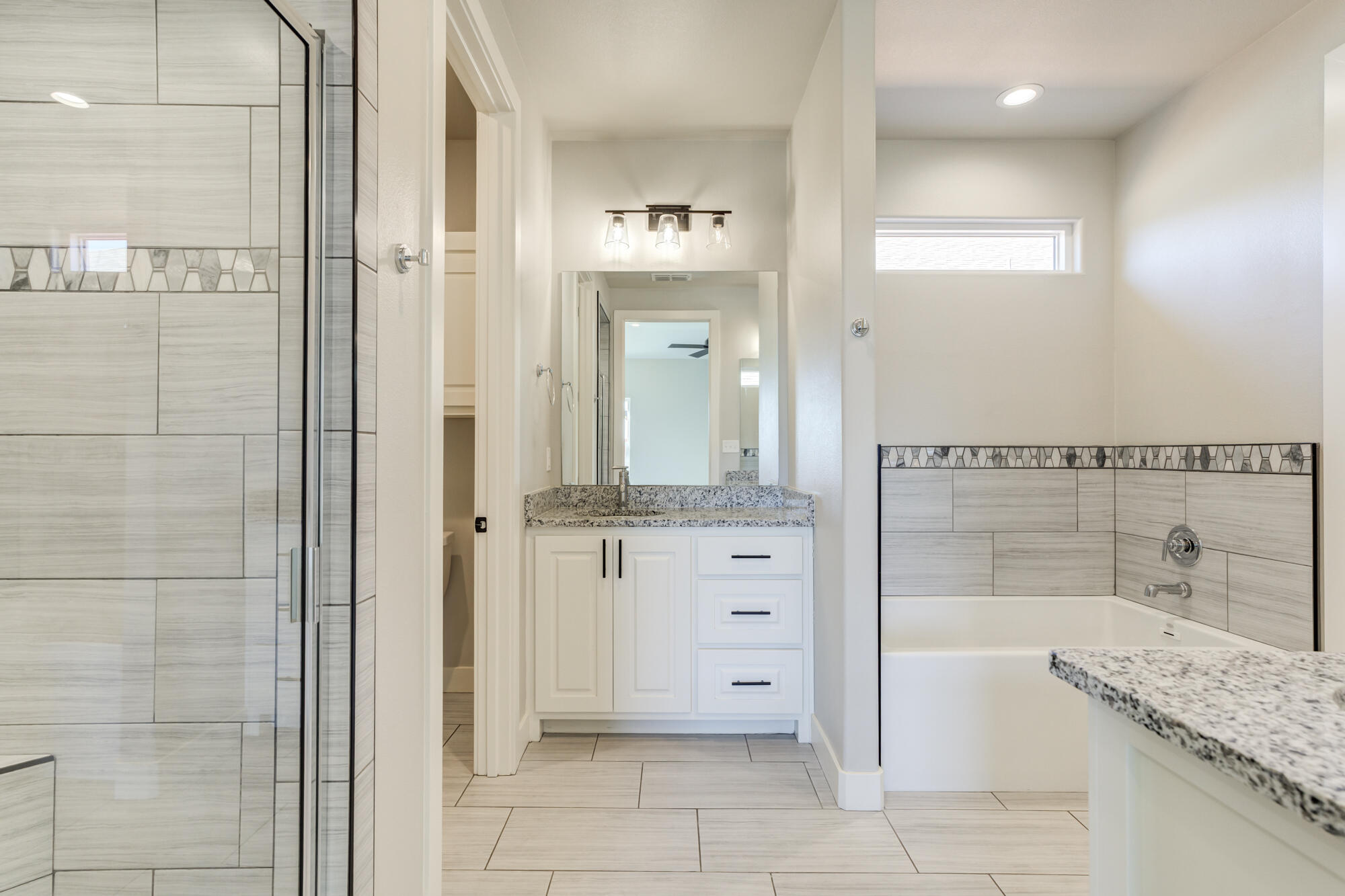 5611 117th Street Lubbock, TX 79424 - Photo 16 of 30 a bathroom with a granite countertop sink a mirror and a bathtub