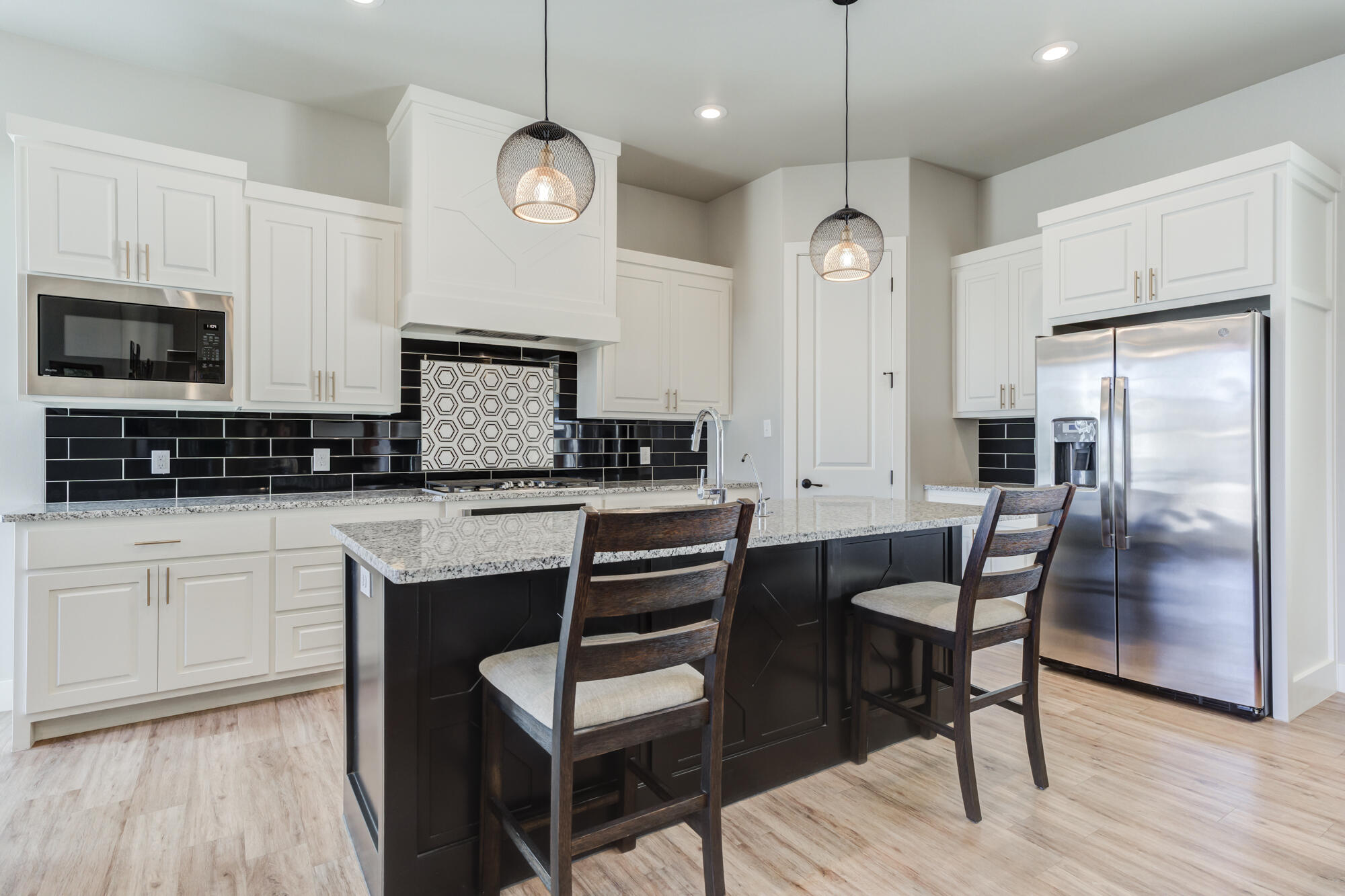 5611 117th Street Lubbock, TX 79424 - Photo 4 of 30 a kitchen with stainless steel appliances granite countertop a stove a sink a refrigerator a microwave oven with white cabinets and wooden floor