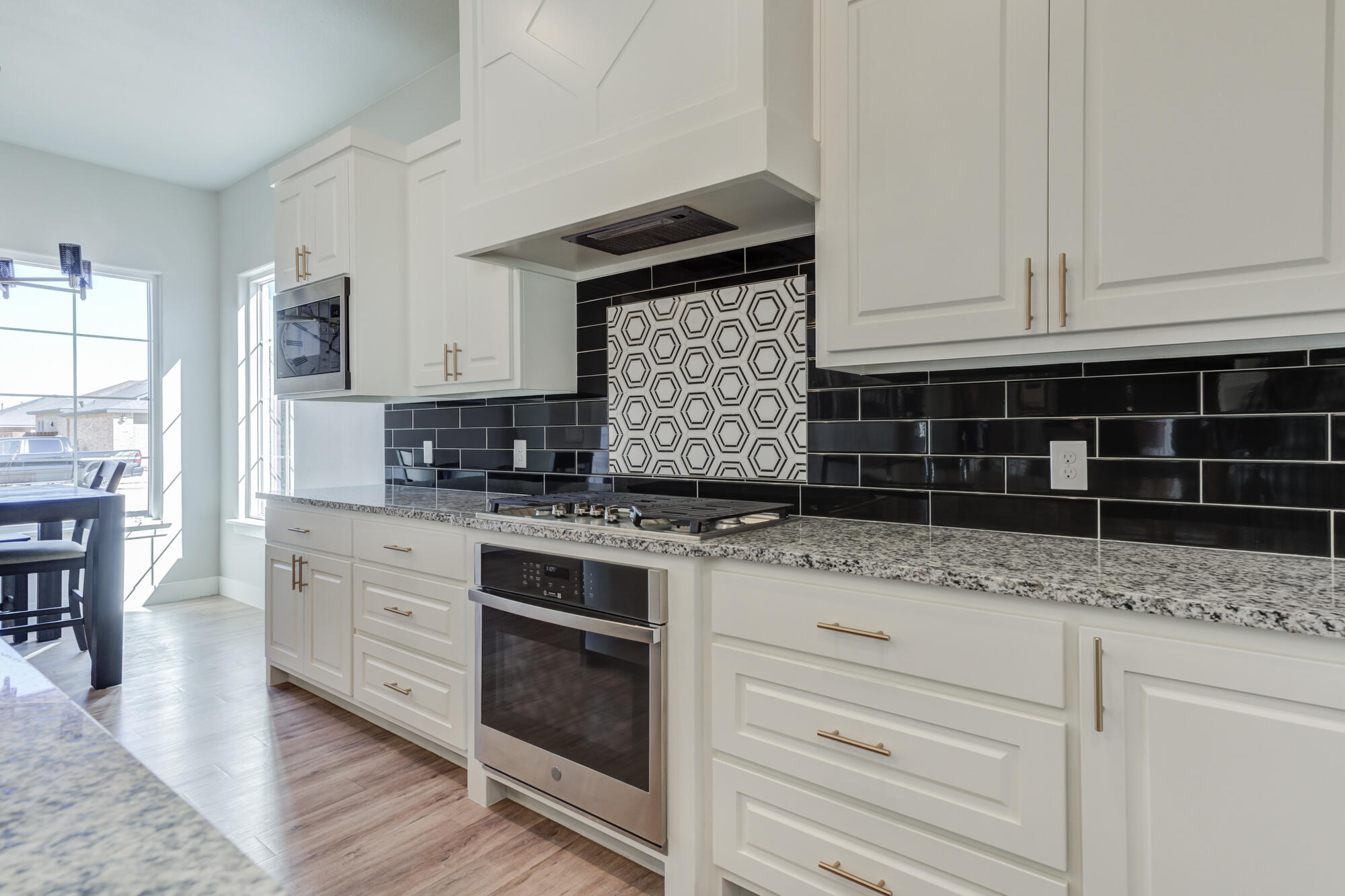 5611 117th Street Lubbock, TX 79424 - Photo 9 of 30 a kitchen with granite countertop a stove a sink and white cabinets