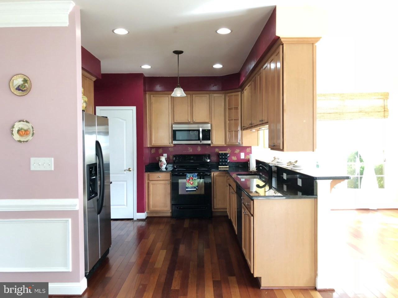 6602 Aaron Mee Way Baltimore, MD 21237 - Photo 12 of 30 a kitchen with a refrigerator a stove top oven a sink and wooden floor