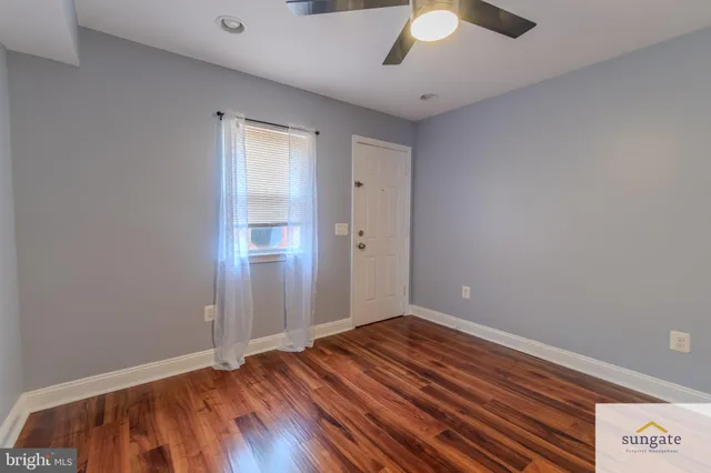wooden floor in an empty room with a chandelier fan