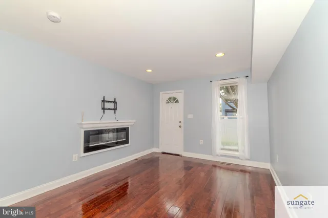 a view of empty room with a fireplace and wooden floor