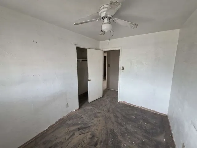 an empty room with a ceiling fan and carpet