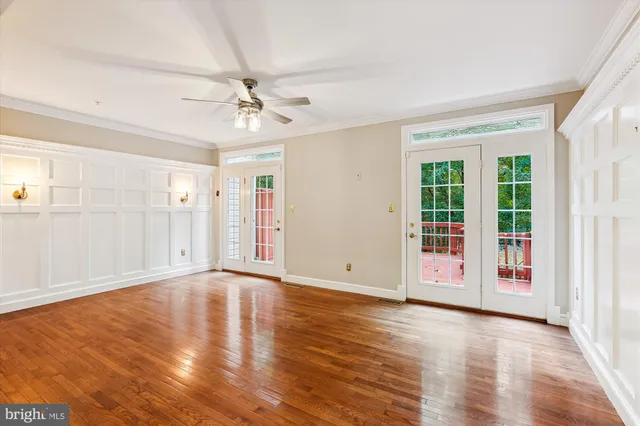 a view of an empty room with wooden floor and a ceiling fan