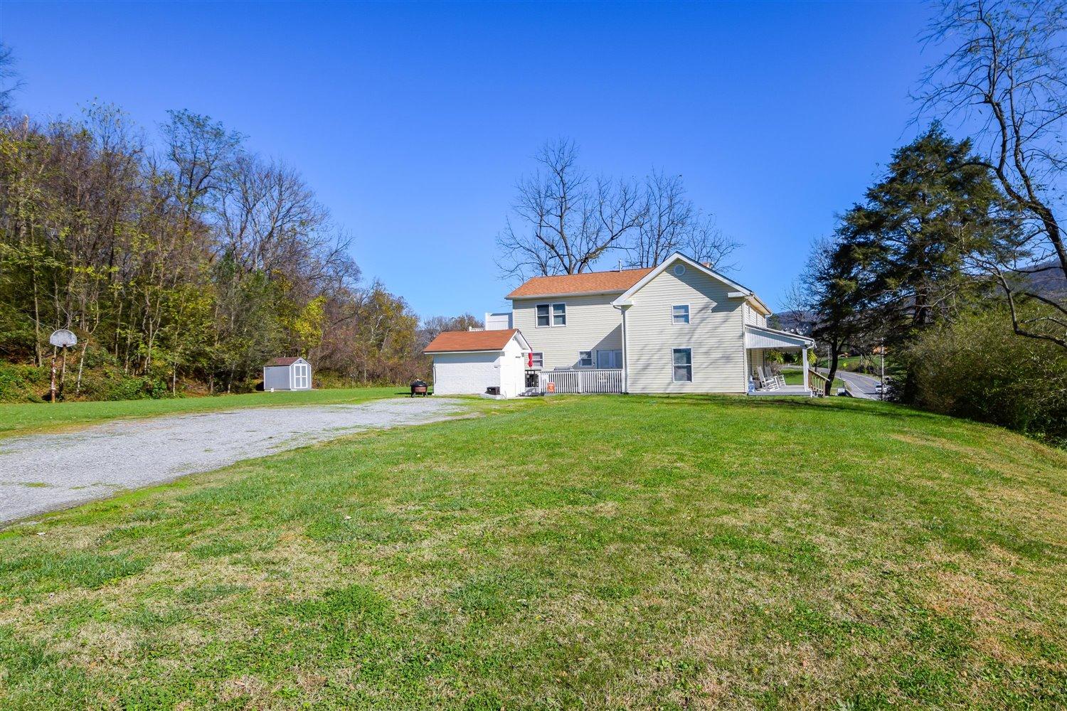 2677 Webster Road Blue Ridge, VA 24064 - Photo 22 of 35 a view of a white house with a big yard and large trees