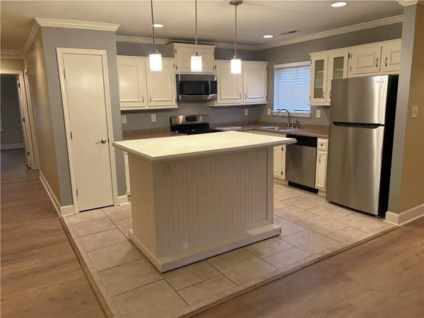 a kitchen with a refrigerator a microwave oven and a sink with wooden floor