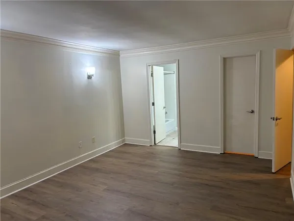 a view of an empty room with wooden floor and closet