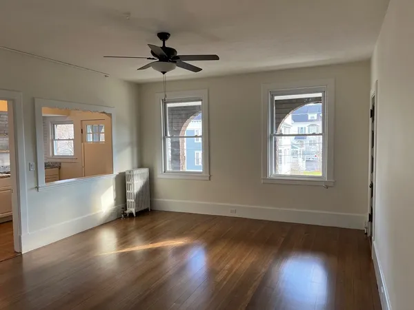 a view of empty room with wooden floor and fan