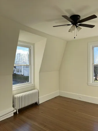 an empty room with wooden floor fan and windows
