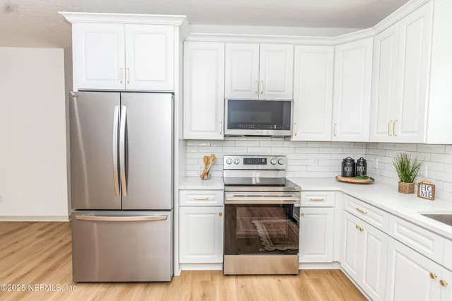 a kitchen with a refrigerator stove and white cabinets