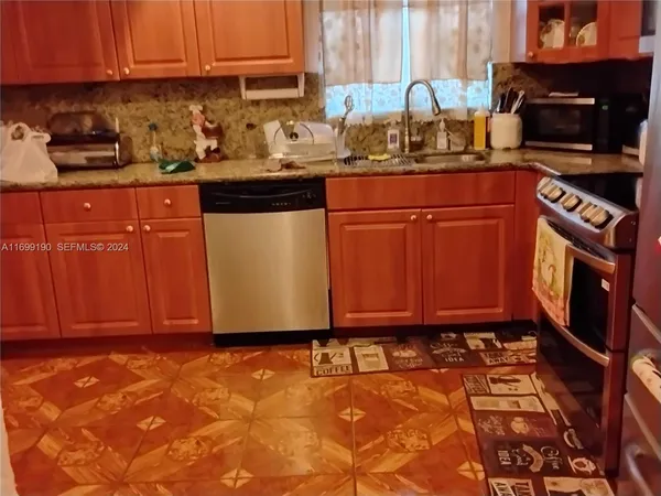 a kitchen with granite countertop a stove top oven a sink a counter space and cabinets