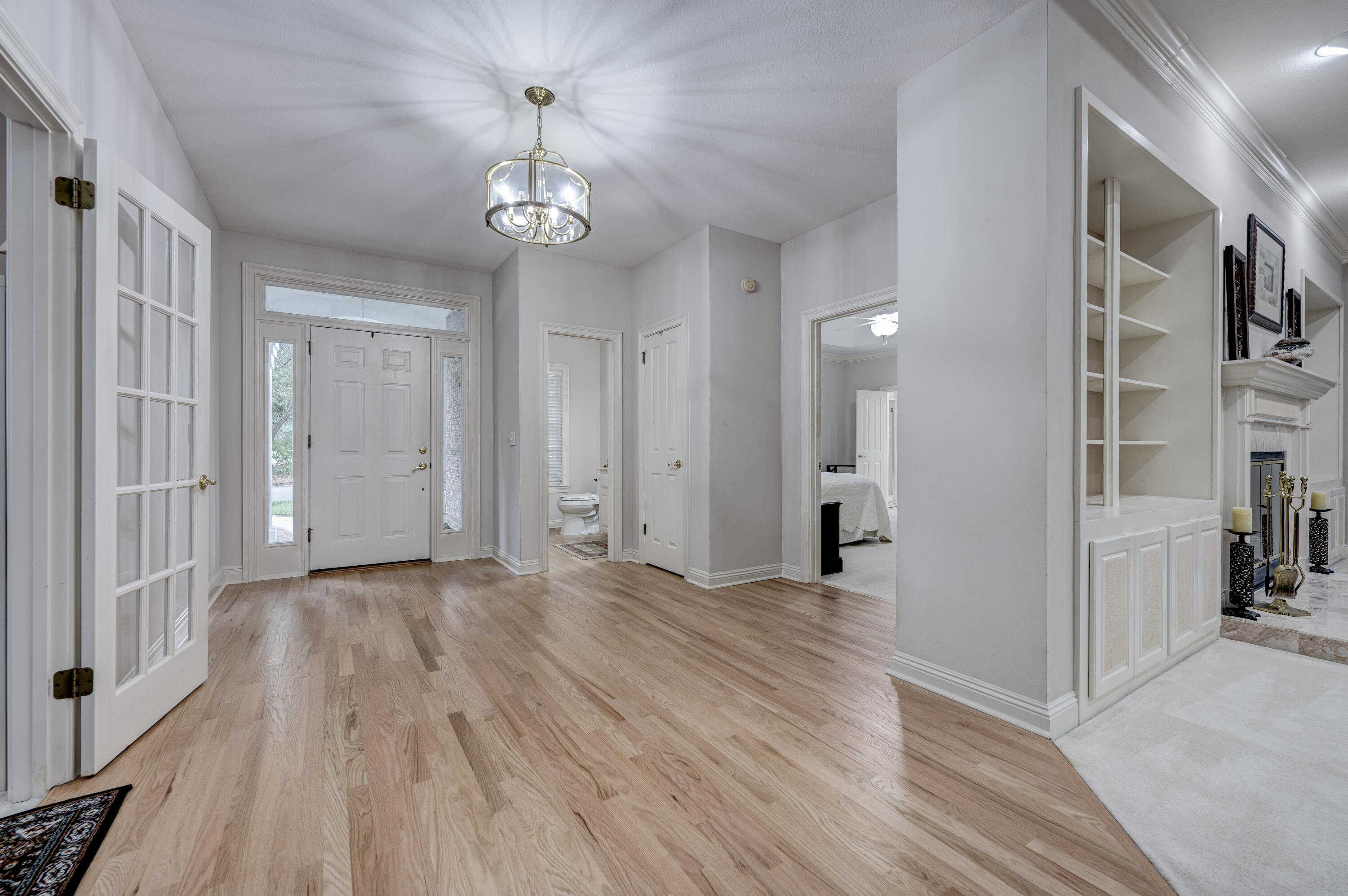 4418 Windrush Drive Niceville, FL 32578 - Photo 4 of 66 a view of a hallway with wooden floor and a chandelier