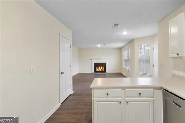 a view of a hallway to room with wooden floor