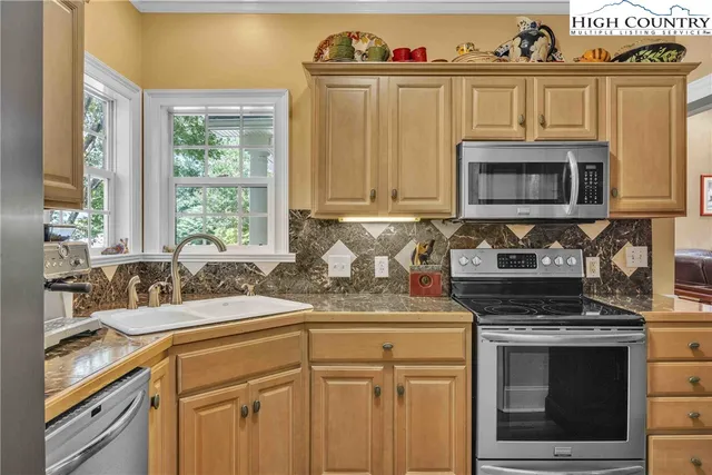 a kitchen with stainless steel appliances granite countertop a refrigerator a stove and a sink with wooden floor