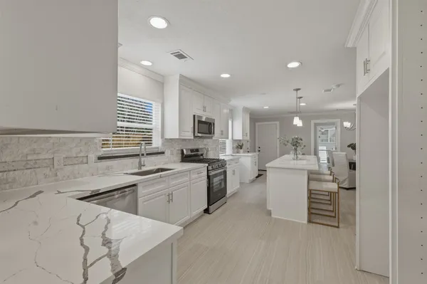 a large white kitchen with lots of counter space and furniture