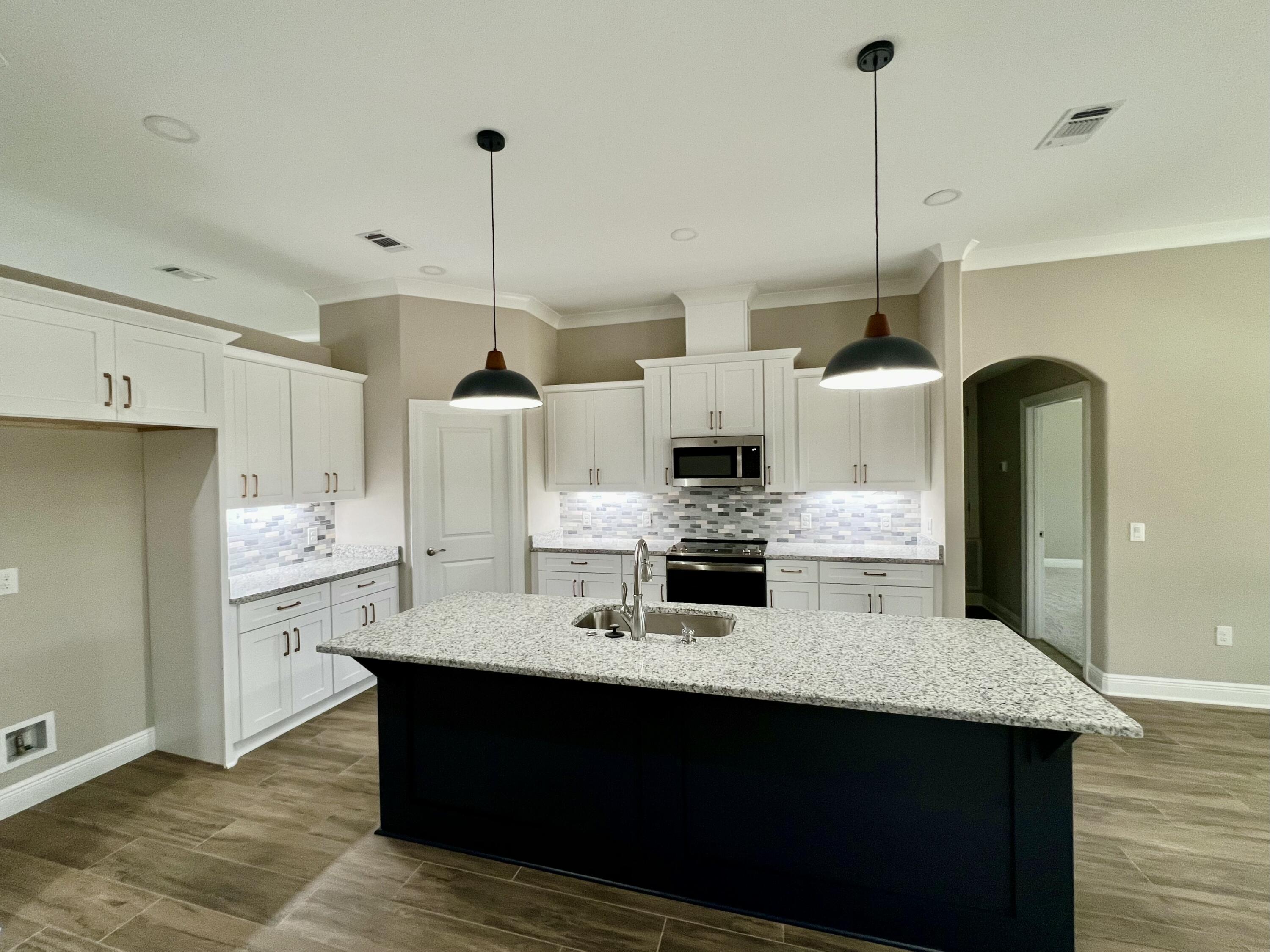 a kitchen with stainless steel appliances kitchen island a refrigerator a stove a sink dishwasher with wooden floor and cabinets