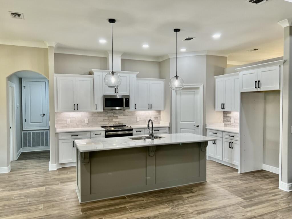 7586 Vinca Street Navarre, FL 32566 - Photo 5 of 44 a kitchen with kitchen island granite countertop a sink cabinets and stainless steel appliances