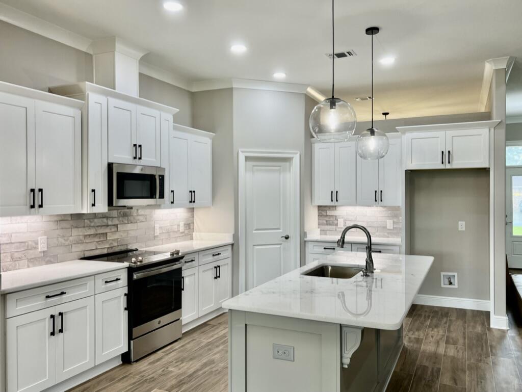 7586 Vinca Street Navarre, FL 32566 - Photo 6 of 44 a kitchen with stainless steel appliances a sink a stove a refrigerator a center island and cabinets